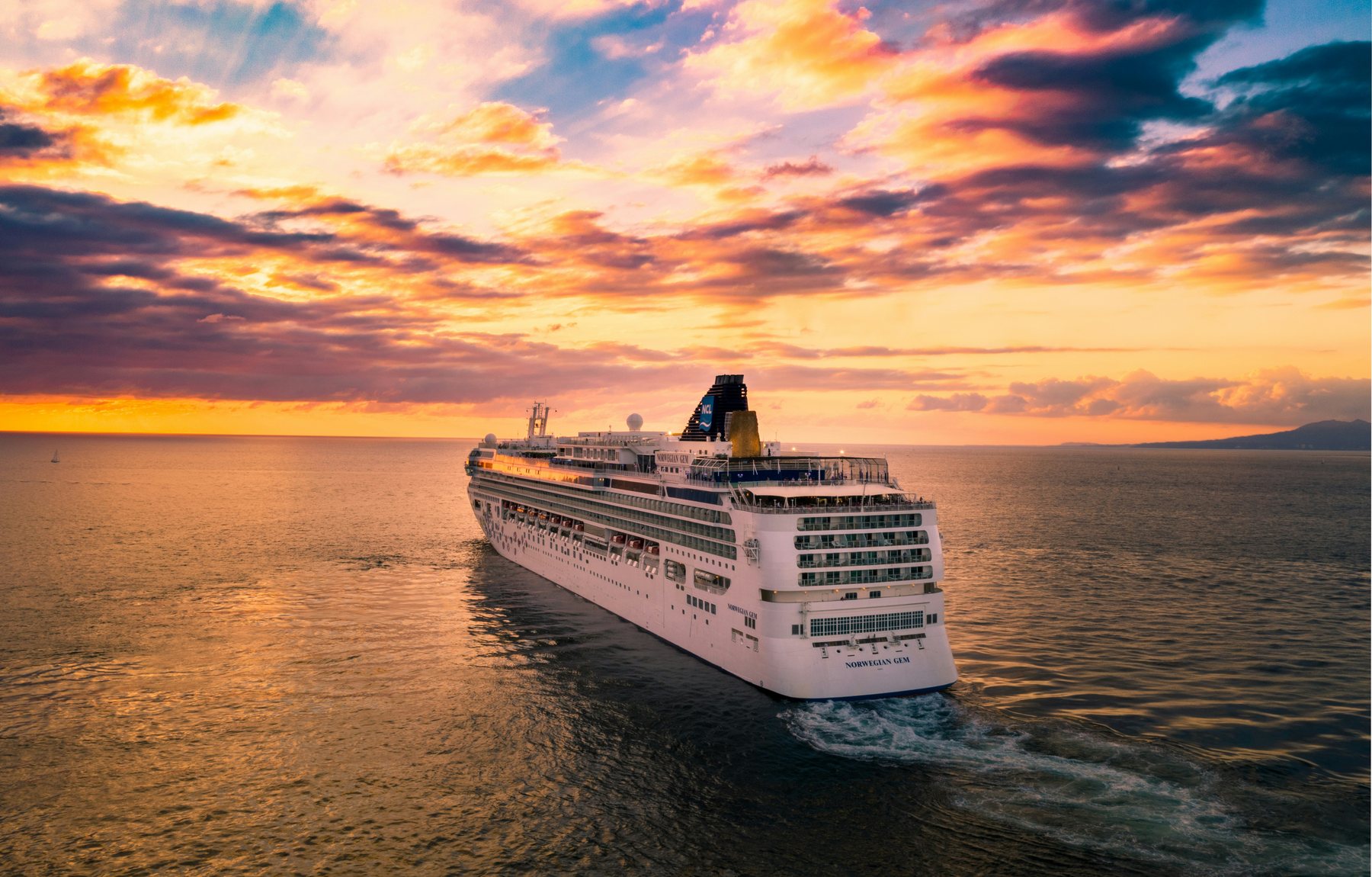 cruise ship sailing into a golden ocean sunset
